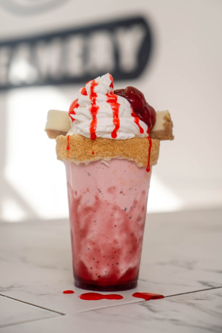 Strawberry milkshake with whipped cream and sauce.