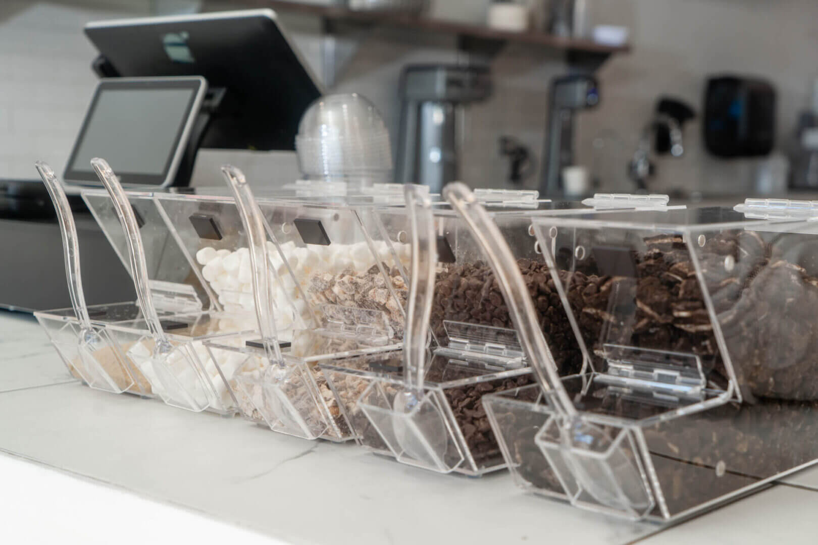 Toppings in clear containers on counter.